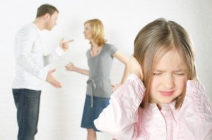 blond child with hands over ears while parents argue