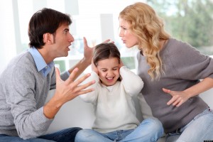 Parents fighting with child's hands over ears