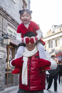 Parent carrying child on shoulders dressed in holiday attire